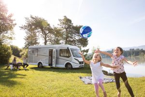 Hymer motorhome in the countryside with kids playing around